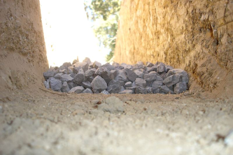 French drain trench lined with base gravel before the pipe goes in